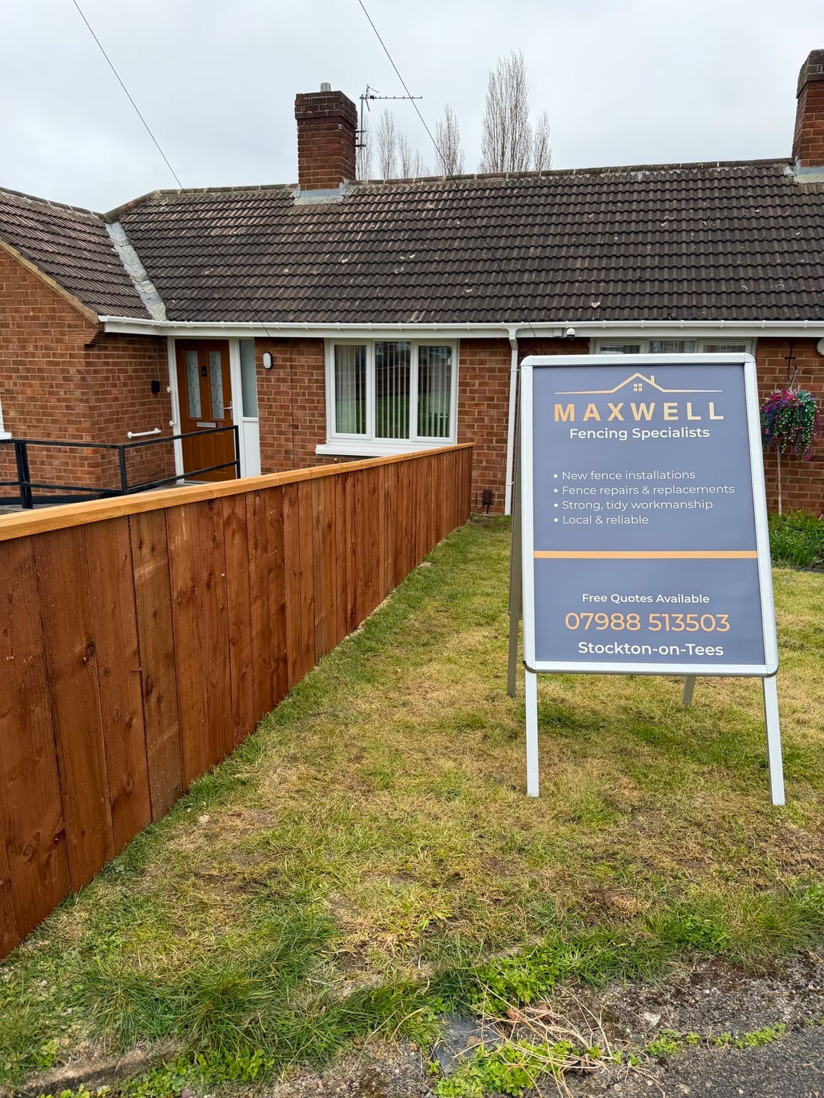 The Maxwell sign board on a customer's front lawn beside a new fence