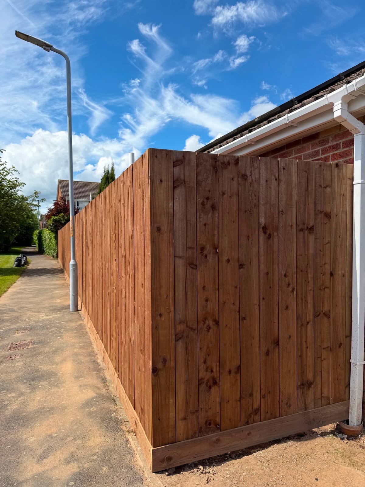 A long run of brown closeboard fencing with gravel boards beside a public footpath