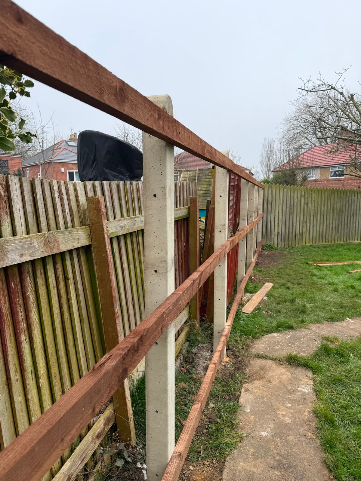 Mid-job — new concrete posts and rails in line with the old fence still standing