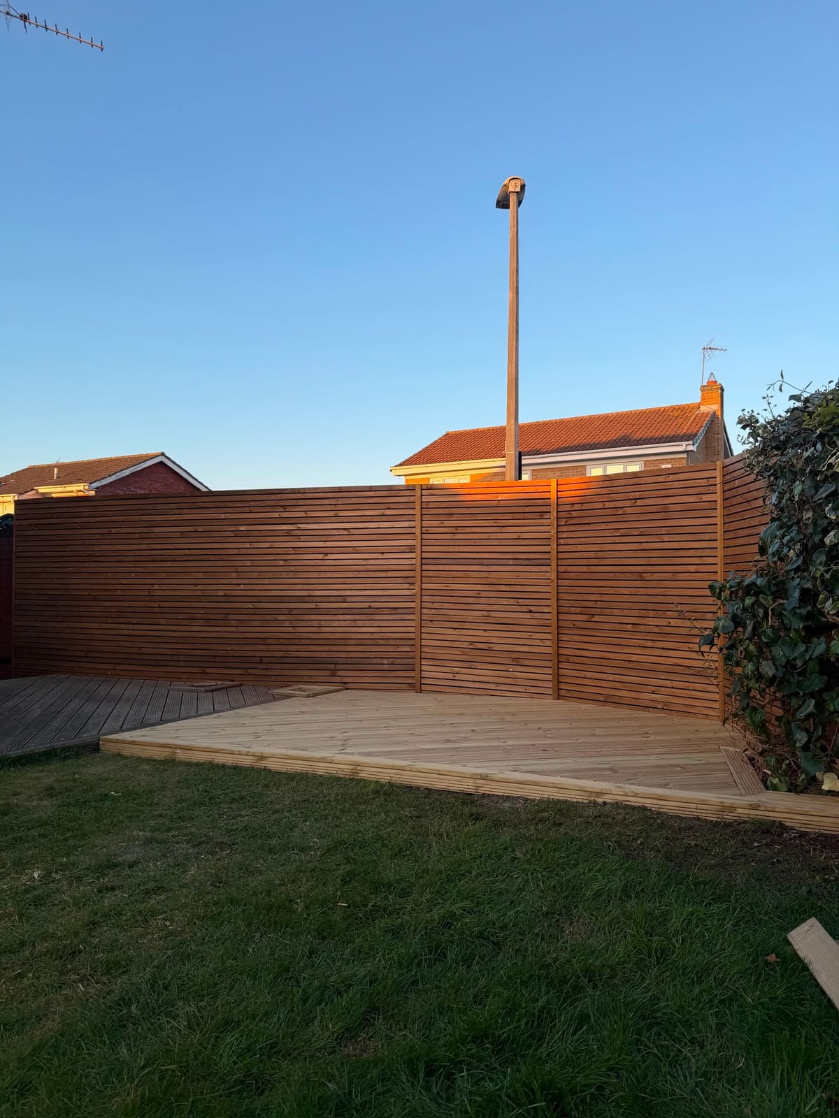 Venetian slatted fence and new decking lit by golden evening sun